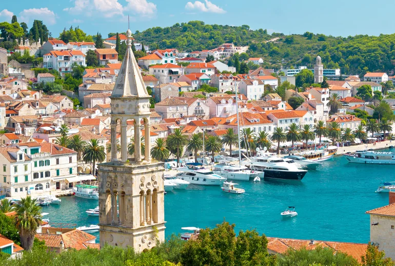Hvar town harbour with stone campanile and palm-lined waterfront